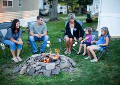 Mom, Dad, Grandmother, and two kids around campfire roasting marshmallows